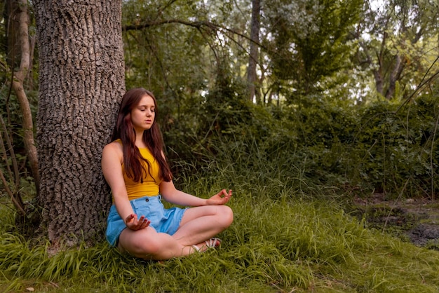 Photo young caucasian girl meditating in the park