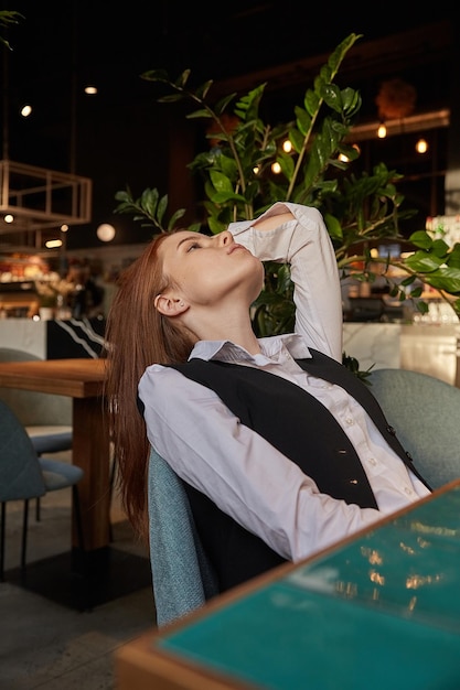 Young caucasian girl with long hair lying on chair at cafe with her chin up