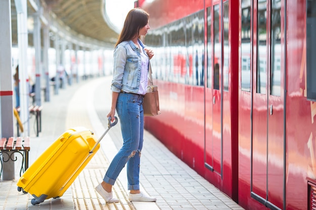 Young caucasian girl with luggage at station traveling by train