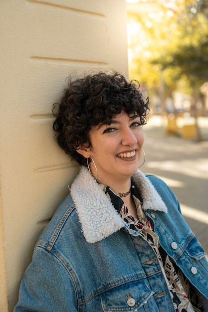 Young caucasian girl with short curly hair smiling on camera in a sunny day