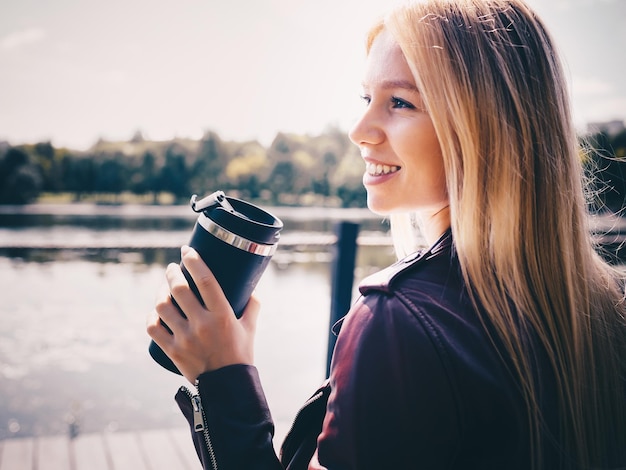 Young caucasian girl with wireless headphones in the park using tablet phone and smiling