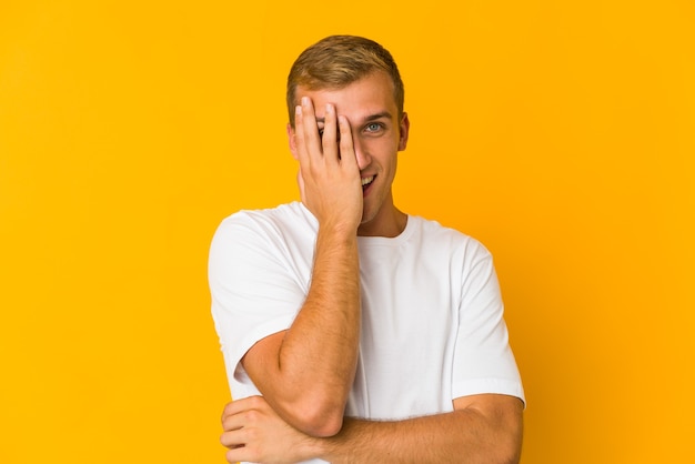 Young caucasian handsome man having fun covering half of face with palm.