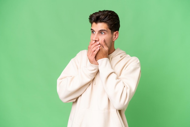 Young caucasian handsome man over isolated background covering mouth and looking to the side