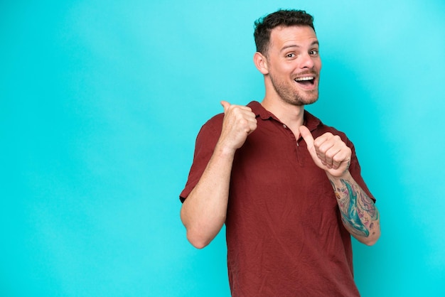 Young caucasian handsome man isolated on blue background pointing to the side to present a product