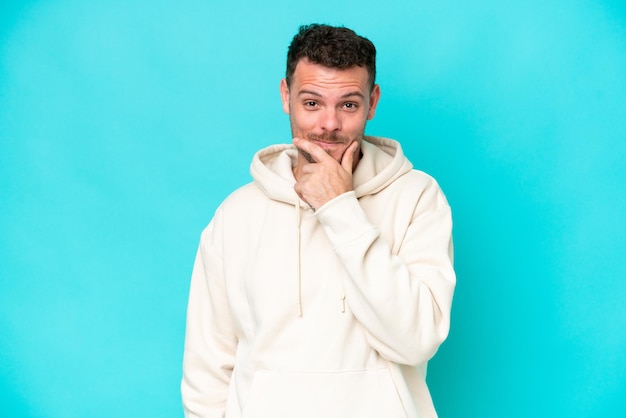 Young caucasian handsome man isolated on blue background thinking