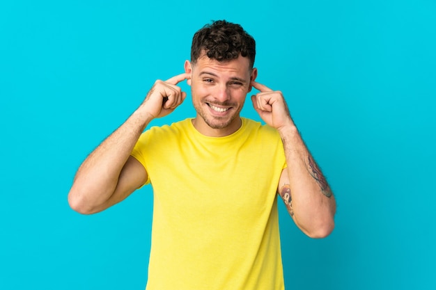 Young caucasian handsome man isolated on blue frustrated and coning ears