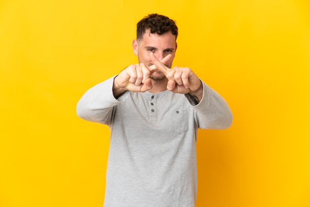 Young caucasian handsome man isolated making stop gesture with her hand to stop an act