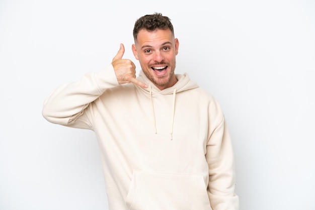 Young caucasian handsome man isolated on white background making phone gesture Call me back sign