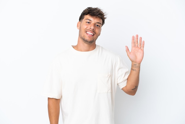 Young caucasian handsome man isolated on white background saluting with hand with happy expression