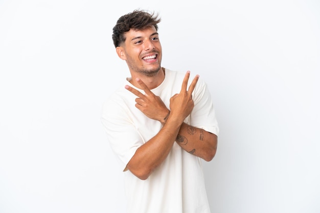 Young caucasian handsome man isolated on white background smiling and showing victory sign