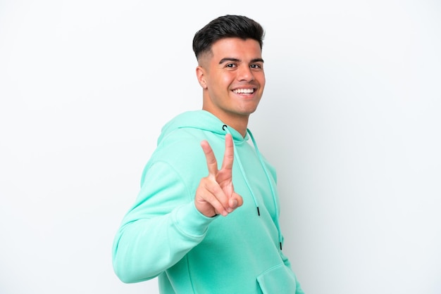 Young caucasian handsome man isolated on white background smiling and showing victory sign