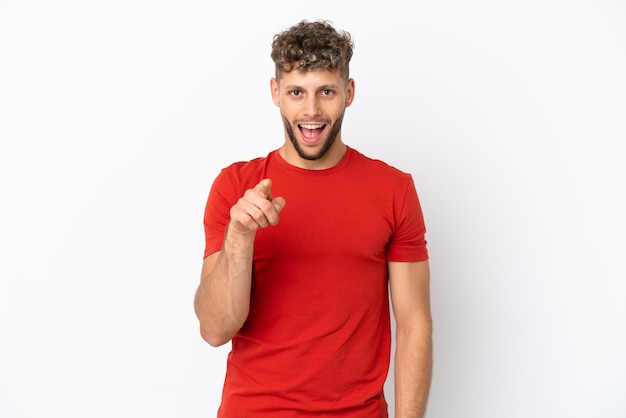 Young caucasian handsome man isolated on white background surprised and pointing front