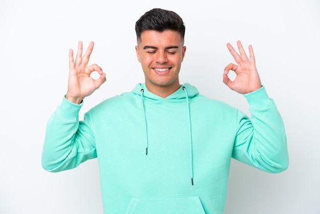 Young caucasian handsome man isolated on white background in zen pose