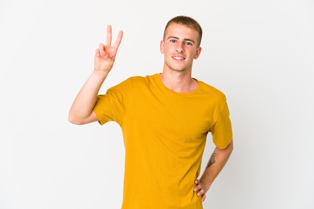 Young caucasian handsome man joyful and carefree showing a peace symbol with fingers.