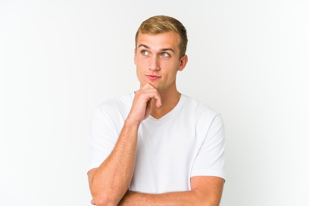 Young caucasian handsome man looking sideways with doubtful and skeptical expression.