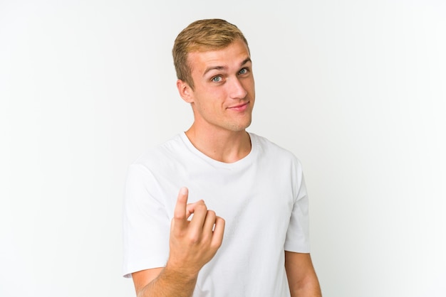 Young caucasian handsome man pointing with finger at you as if inviting come closer.