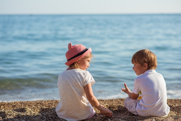 Young caucasian kids on the ocean shore on a sunny summer day