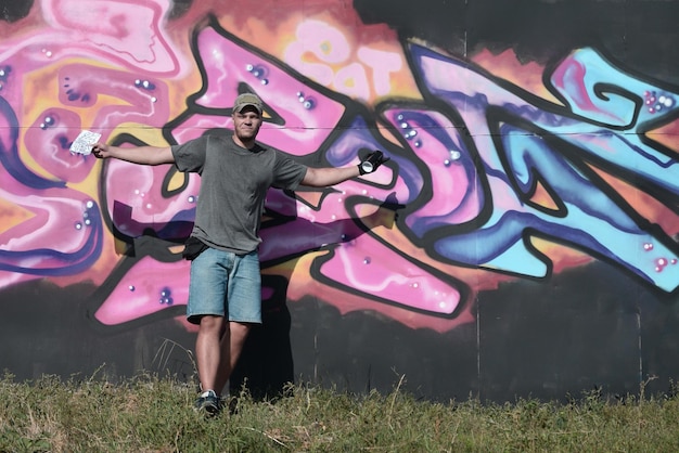 Young caucasian male graffiti artist drawing big street art painting in blue and pink tones