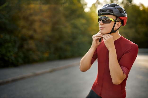 Young caucasian male is wearing helmet for riding a bike outdoors looking at side