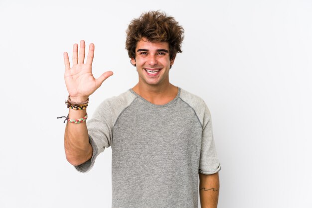 Young caucasian man against a white background isolated smiling cheerful showing number five with fingers.