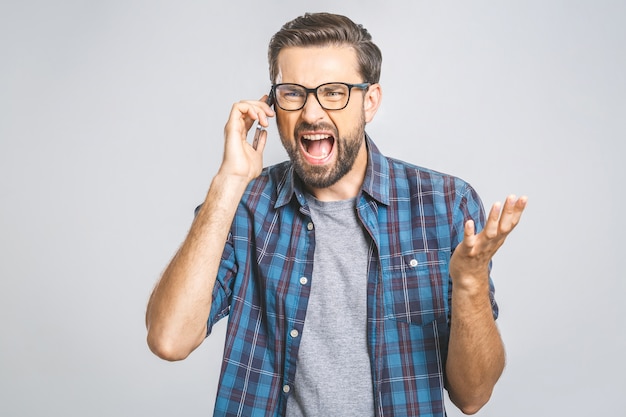 Young caucasian man angry, frustrated and furious with his phone, angry with customer service. Isolated.