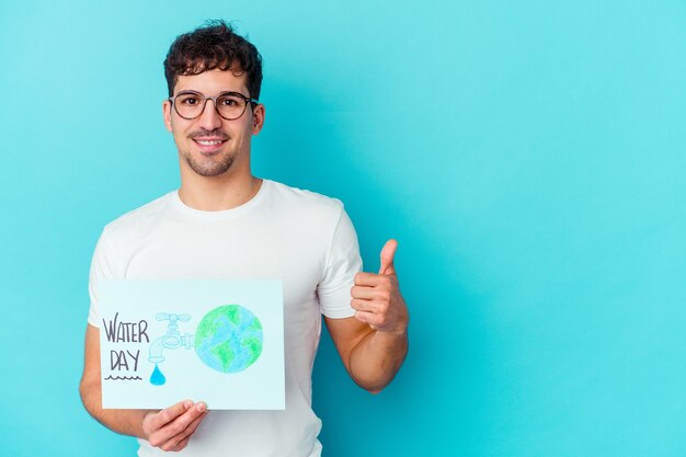 Young caucasian man celebrating world water day isolated smiling and raising thumb up