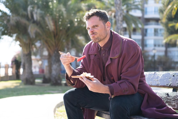 Young caucasian man eating sashimi at outdoors