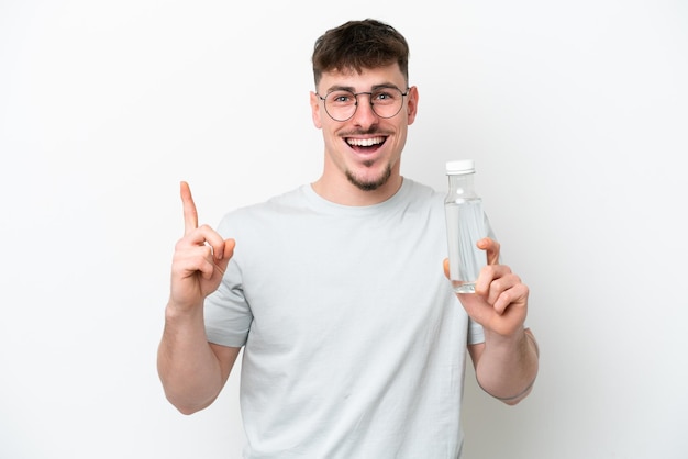 Young caucasian man holding a bottle of water isolated on white background pointing up a great idea