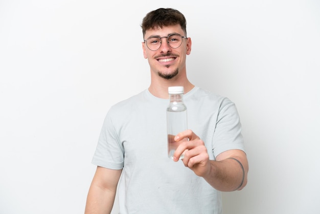 Young caucasian man holding a bottle of water isolated on white background with happy expression