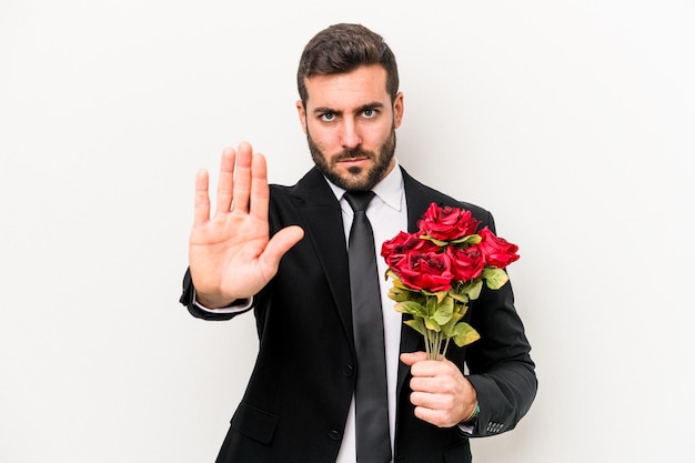 Young caucasian man holding a bouquet of flowers isolated on white background standing with outstretched hand showing stop sign preventing you