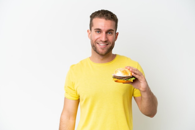 Young caucasian man holding a burger isolated on white background with happy expression