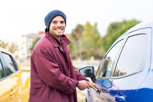 Young caucasian man holding car keys at outdoors