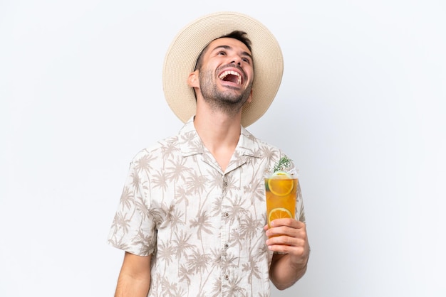 Young caucasian man holding a cocktail isolated on white background laughing