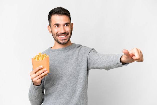 Young caucasian man holding fried chips over isolated white background giving a thumbs up gesture