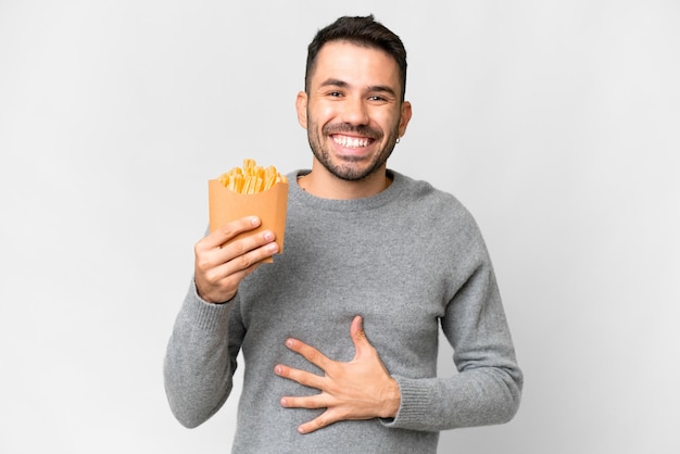 Young caucasian man holding fried chips over isolated white background smiling a lot