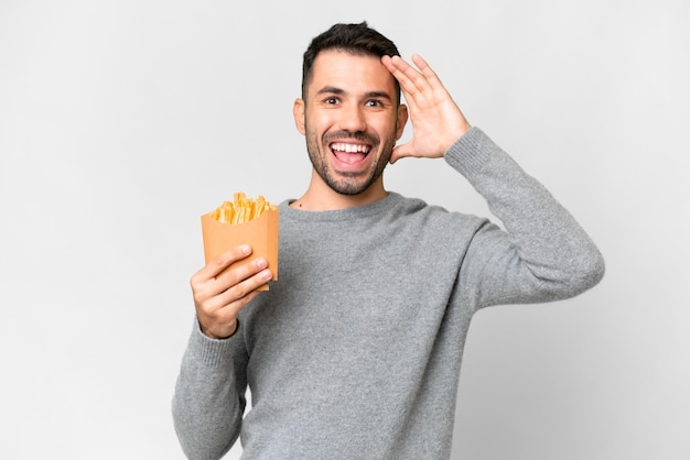 Young caucasian man holding fried chips over isolated white background with surprise expression