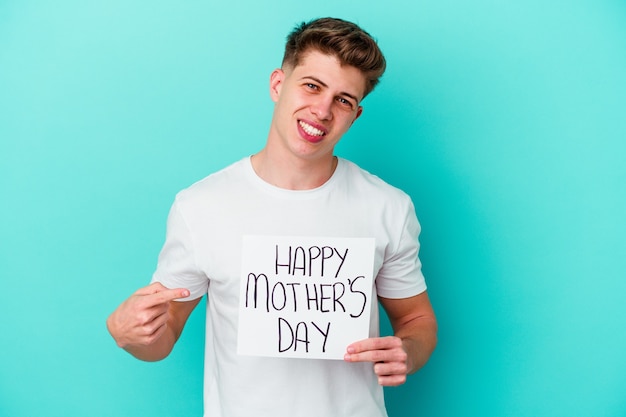 Young caucasian man holding a Happy Mothers day placard on blue