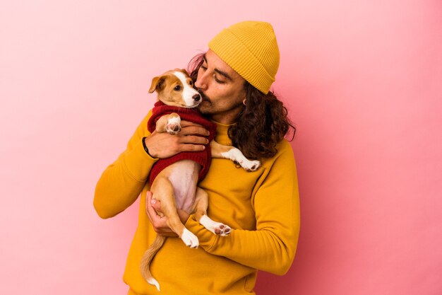 Photo young caucasian man holding his puppy isolated on pink background