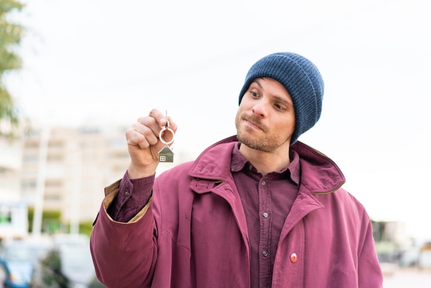 Young caucasian man holding home keys at outdoors