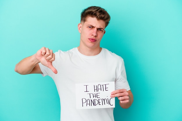 Photo young caucasian man holding a i hate the pandemic placard isolated on blue wall