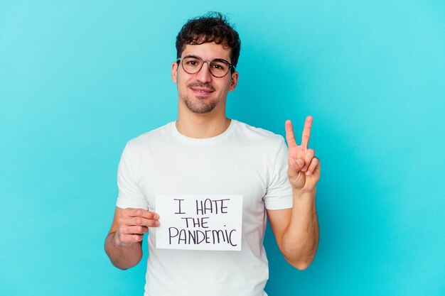 Young caucasian man holding a I hate the pandemic placard showing number two with fingers.