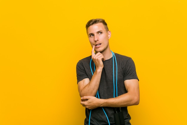 Young caucasian man holding a jump rope relaxed thinking about something looking at a copy space.