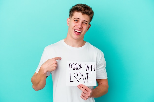 Young caucasian man holding a made with love placard isolated on blue background