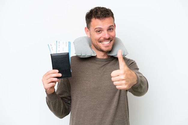 Young caucasian man holding a passport isolated on white background with thumbs up because something good has happened