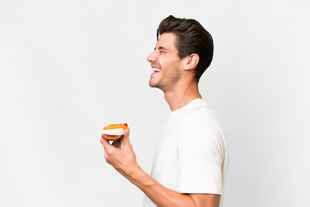 Young caucasian man holding sashimi over isolated white background laughing in lateral position