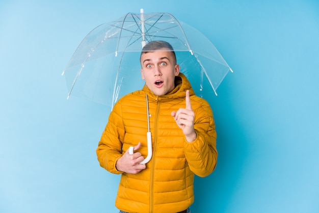 Young caucasian man holding an umbrella having an idea