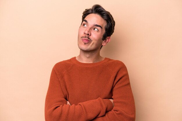 Young caucasian man isolated on beige background dreaming of achieving goals and purposes