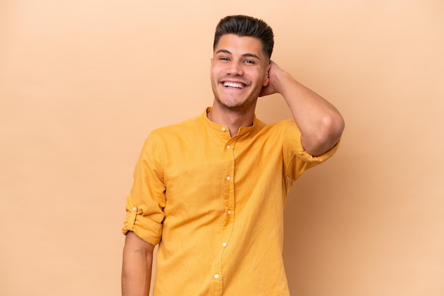 Young caucasian man isolated on beige background laughing