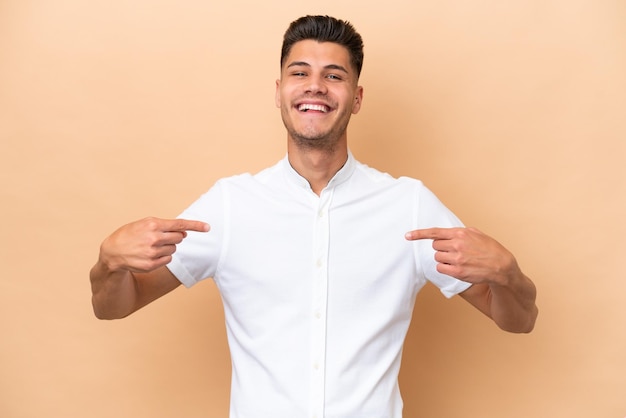 Young caucasian man isolated on beige background proud and selfsatisfied