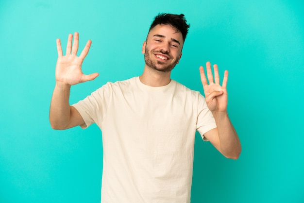 Young caucasian man isolated on blue background counting nine with fingers